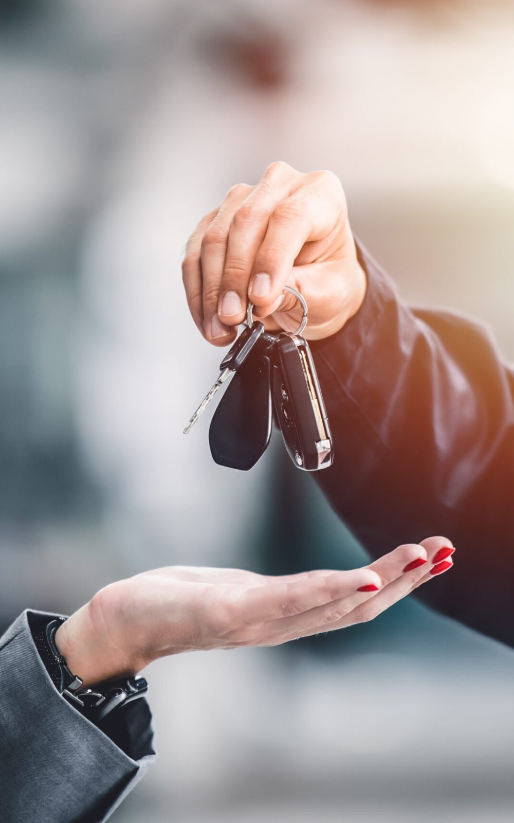 Closeup male hand giving a car key for vehicle loan credit financial, lease or rental concept